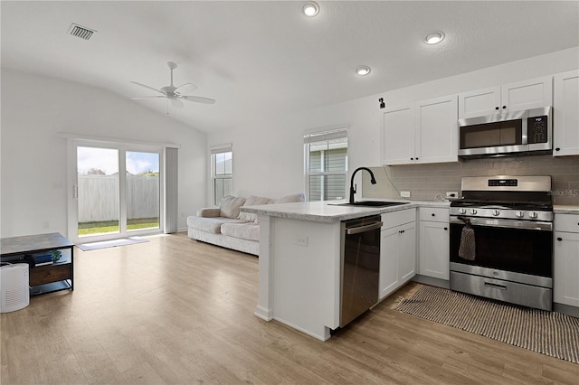 kitchen with kitchen peninsula, sink, stainless steel appliances, and white cabinets