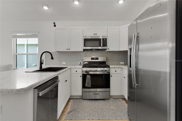 kitchen featuring white cabinetry, kitchen peninsula, sink, and stainless steel appliances