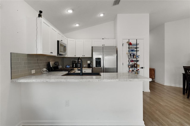 kitchen with stainless steel appliances, light hardwood / wood-style floors, sink, white cabinetry, and kitchen peninsula