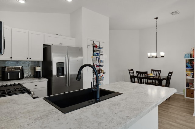 kitchen with sink, white cabinetry, hanging light fixtures, and stainless steel fridge with ice dispenser