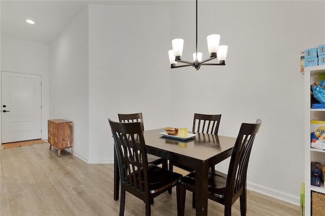 dining area with light wood-type flooring and a notable chandelier