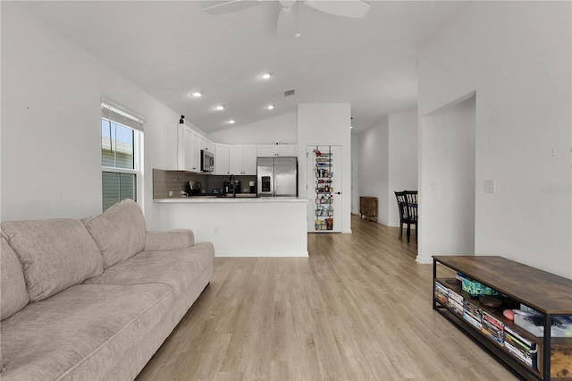 living room with ceiling fan, light wood-type flooring, and lofted ceiling