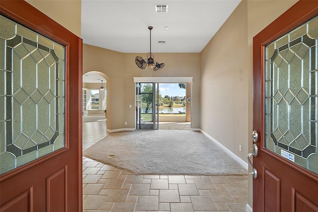 carpeted entryway featuring an inviting chandelier and a water view