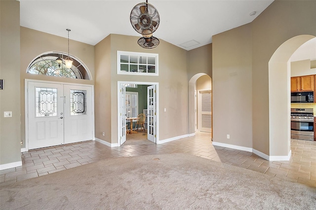 carpeted foyer entrance featuring high vaulted ceiling, french doors, and a chandelier