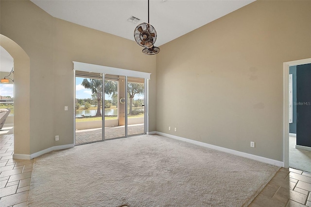 carpeted empty room with a water view and a high ceiling