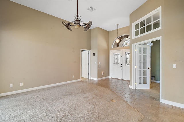 carpeted foyer entrance with a towering ceiling, ceiling fan, and french doors