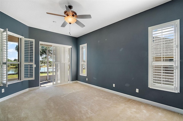 carpeted empty room featuring a water view and ceiling fan