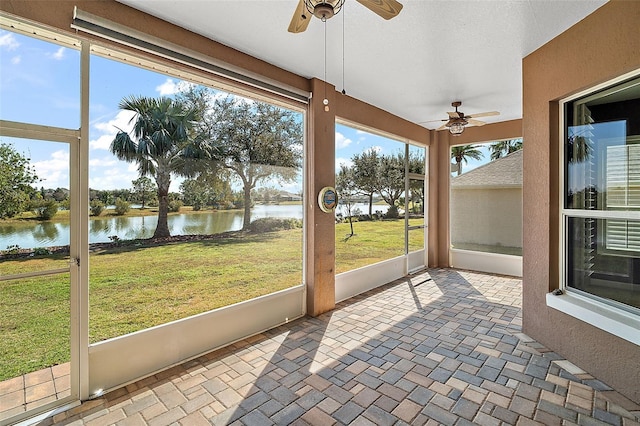 unfurnished sunroom featuring a water view and ceiling fan