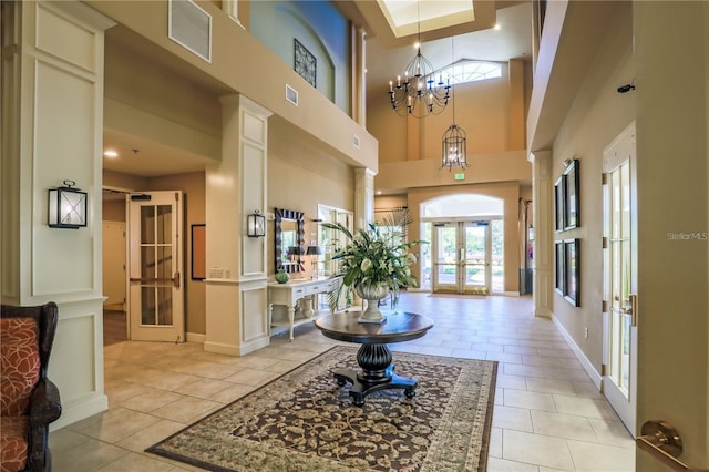 foyer with an inviting chandelier, light tile patterned floors, french doors, and a high ceiling