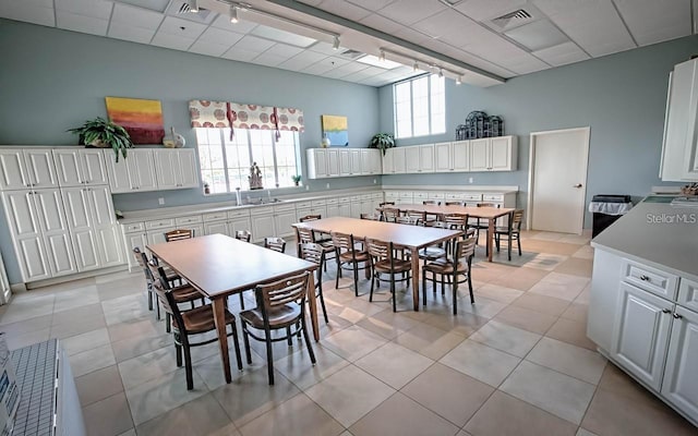 tiled dining space featuring rail lighting, sink, and a paneled ceiling