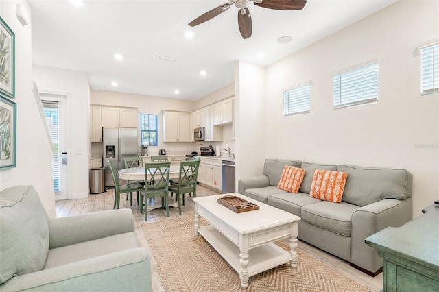 living room with sink, a wealth of natural light, ceiling fan, and light hardwood / wood-style flooring