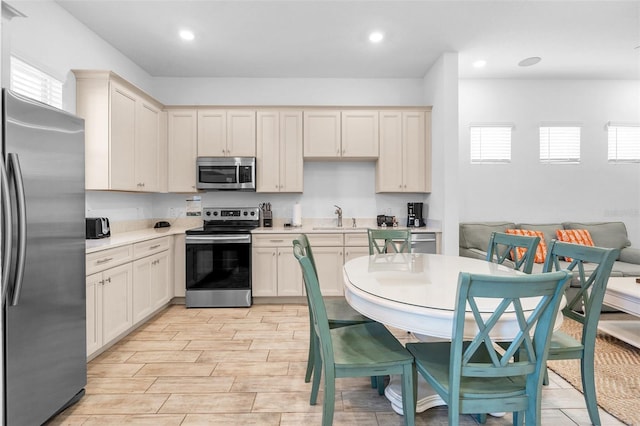 kitchen with appliances with stainless steel finishes, sink, and cream cabinets