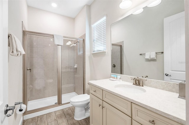 bathroom featuring vanity, a shower with shower door, and toilet