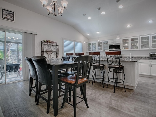 dining room with vaulted ceiling, a wealth of natural light, a notable chandelier, and light wood-type flooring