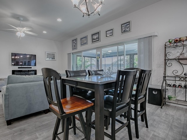 dining room featuring ceiling fan with notable chandelier and light wood-type flooring