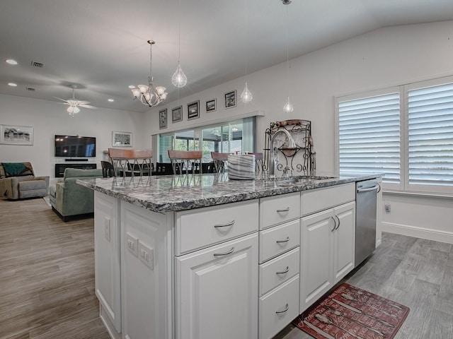 kitchen with stone countertops, pendant lighting, sink, white cabinets, and a center island with sink