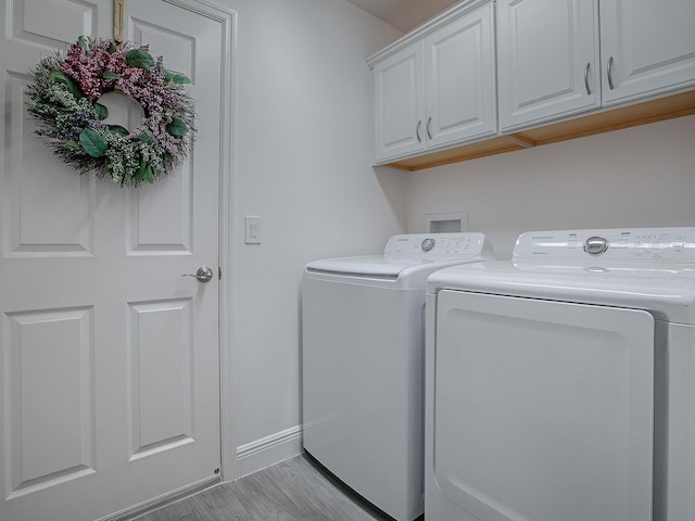 laundry area with cabinets, washer and dryer, and light hardwood / wood-style floors