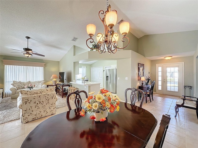 tiled dining room with sink, ceiling fan with notable chandelier, vaulted ceiling, and a textured ceiling