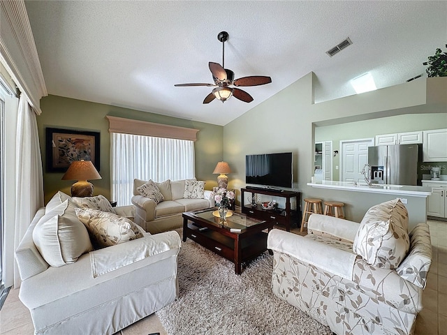 living room featuring ceiling fan, lofted ceiling, and a textured ceiling