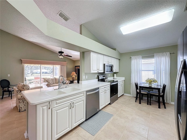 kitchen featuring sink, vaulted ceiling, appliances with stainless steel finishes, kitchen peninsula, and white cabinets