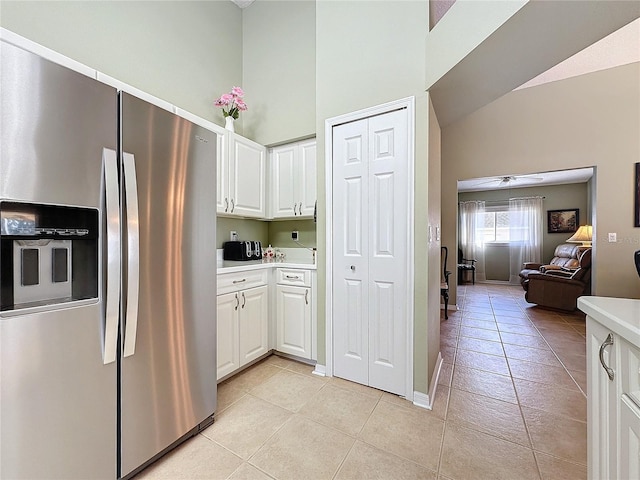 kitchen with stainless steel refrigerator with ice dispenser, white cabinetry, high vaulted ceiling, and light tile patterned floors