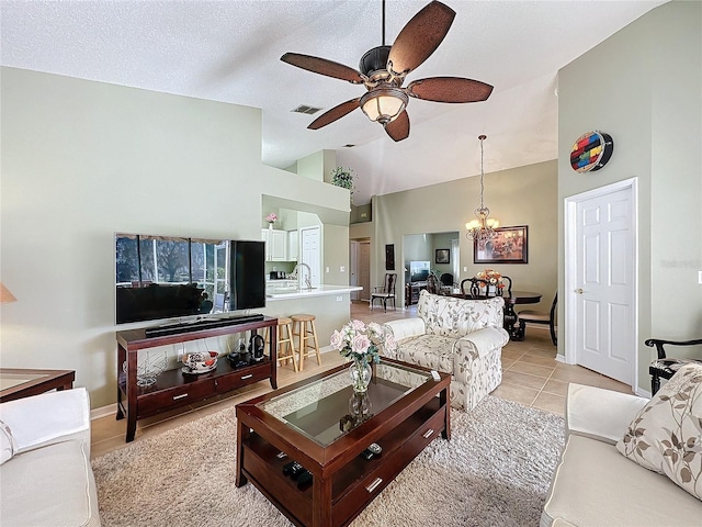 tiled living room featuring ceiling fan with notable chandelier, sink, high vaulted ceiling, and a textured ceiling