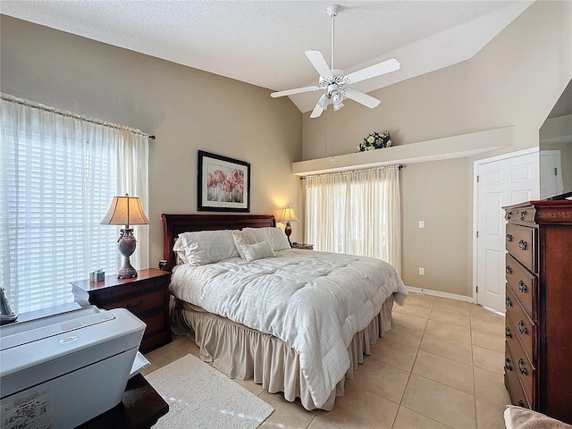 tiled bedroom with ceiling fan, vaulted ceiling, and a textured ceiling