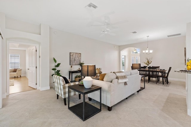 tiled living room with ceiling fan with notable chandelier