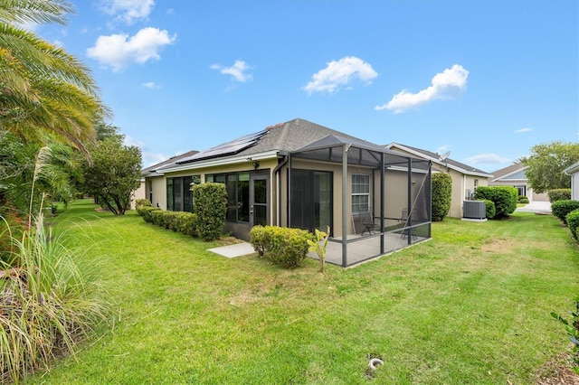 rear view of property featuring a yard, solar panels, and central air condition unit