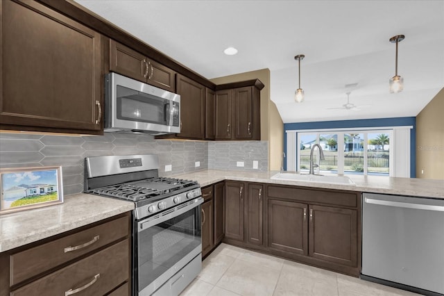 kitchen featuring dark brown cabinetry, sink, hanging light fixtures, appliances with stainless steel finishes, and decorative backsplash