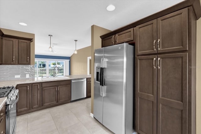 kitchen with pendant lighting, sink, appliances with stainless steel finishes, backsplash, and light stone countertops