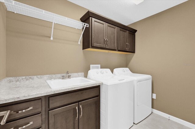 clothes washing area featuring sink, light tile patterned floors, cabinets, and washing machine and clothes dryer