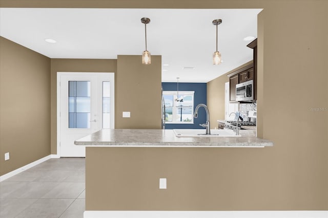 kitchen featuring pendant lighting, sink, stove, light tile patterned floors, and kitchen peninsula