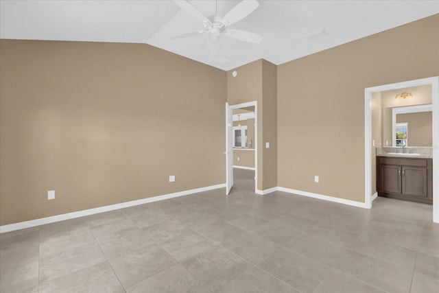 unfurnished bedroom with lofted ceiling, connected bathroom, sink, light tile patterned floors, and ceiling fan