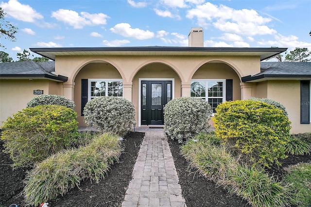 doorway to property featuring a chimney and stucco siding