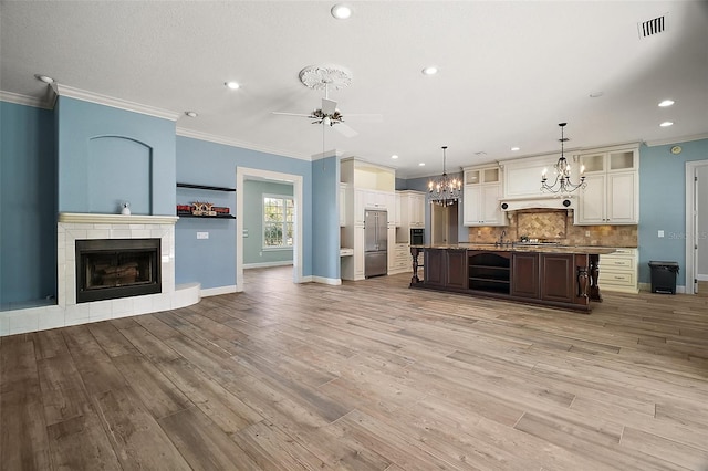 kitchen featuring stainless steel appliances, light wood-style flooring, decorative backsplash, open floor plan, and a tile fireplace