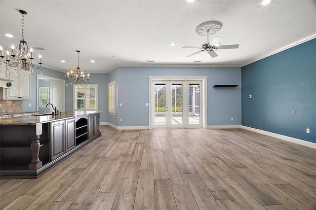 kitchen featuring a sink, baseboards, ornamental molding, light wood-type flooring, and plenty of natural light