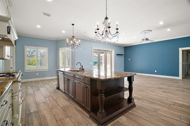 kitchen featuring dark brown cabinetry, visible vents, light wood-style flooring, crown molding, and a sink