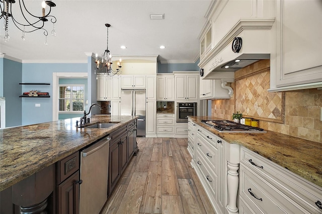 kitchen with stainless steel appliances, premium range hood, a sink, and crown molding