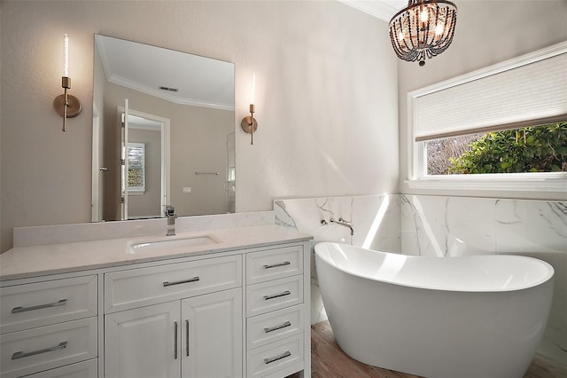 bathroom with visible vents, crown molding, vanity, a freestanding tub, and a chandelier