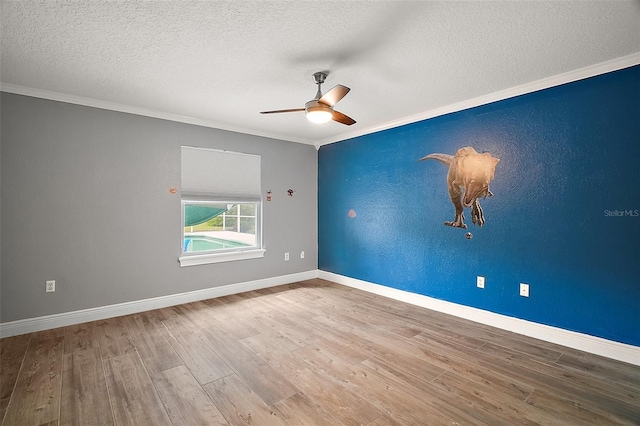 spare room with baseboards, a textured wall, ornamental molding, wood finished floors, and a textured ceiling