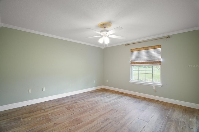 spare room with crown molding, baseboards, and wood finished floors