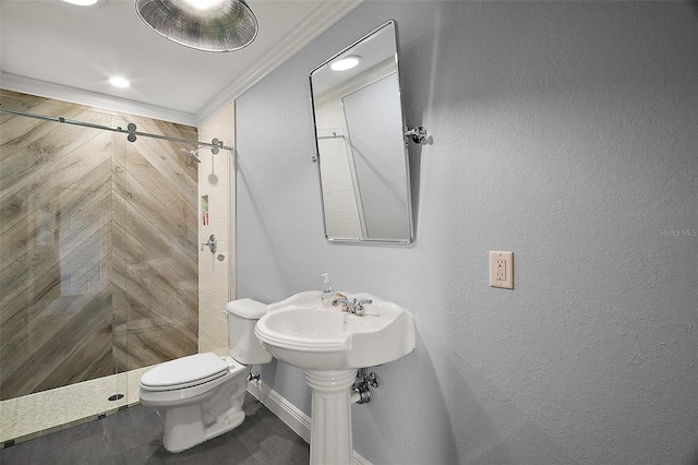 bathroom with baseboards, a tile shower, toilet, and crown molding