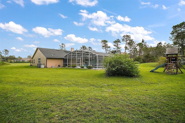 view of yard with glass enclosure, a playground, and central AC unit