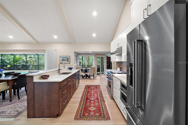 kitchen featuring high quality appliances, white cabinetry, an island with sink, sink, and dark brown cabinets