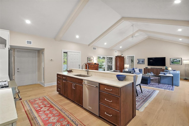 kitchen featuring sink, a kitchen island with sink, vaulted ceiling with beams, stainless steel appliances, and light wood-type flooring