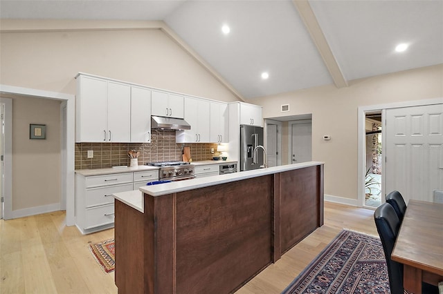 kitchen featuring high end appliances, white cabinetry, an island with sink, and tasteful backsplash