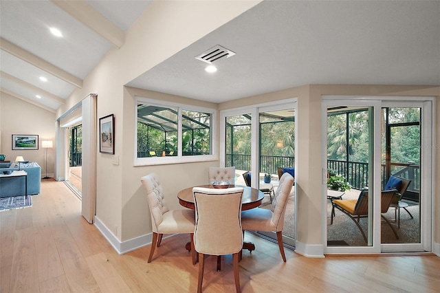 dining area with lofted ceiling with beams and light hardwood / wood-style floors