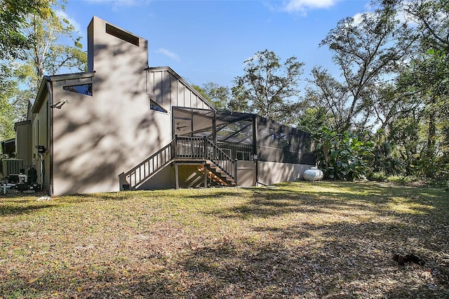 view of side of property featuring cooling unit, a lanai, and a lawn