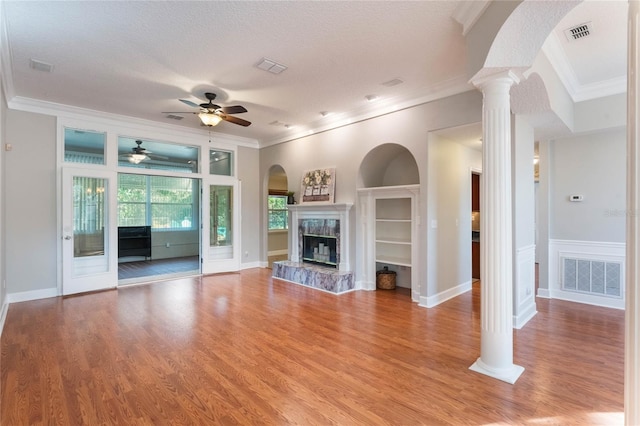 unfurnished living room featuring ornate columns, ornamental molding, a fireplace, and a textured ceiling